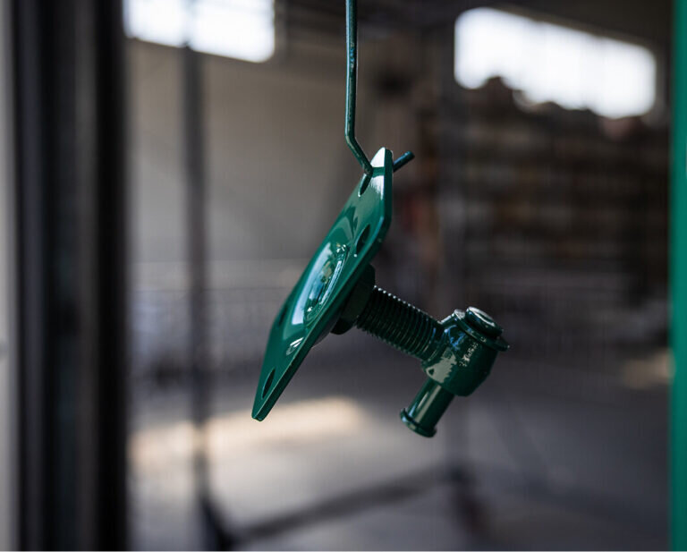 Zielony pomalowany element metalowy zawieszony do lakierowania